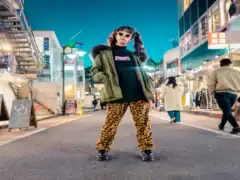 Stylish woman in bold animal print pants and trendy jacket at night in city street.