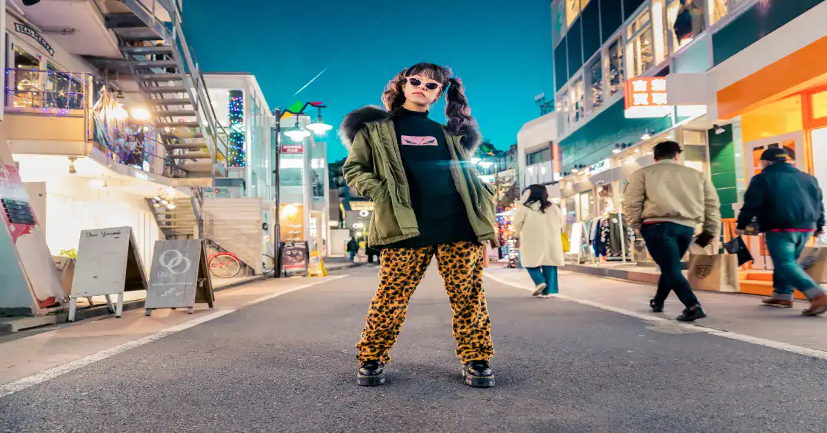 Stylish woman in bold animal print pants and trendy jacket at night in city street.